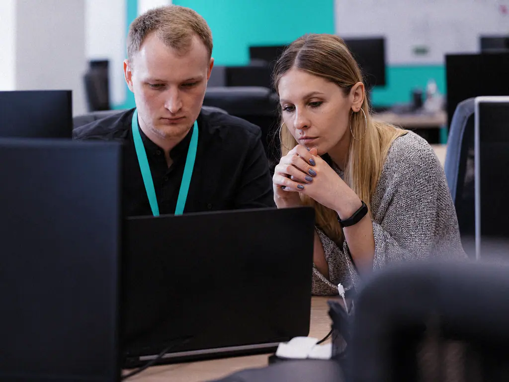 Deux collègues cherchant ensemble une information sur un poste de travail, en open space