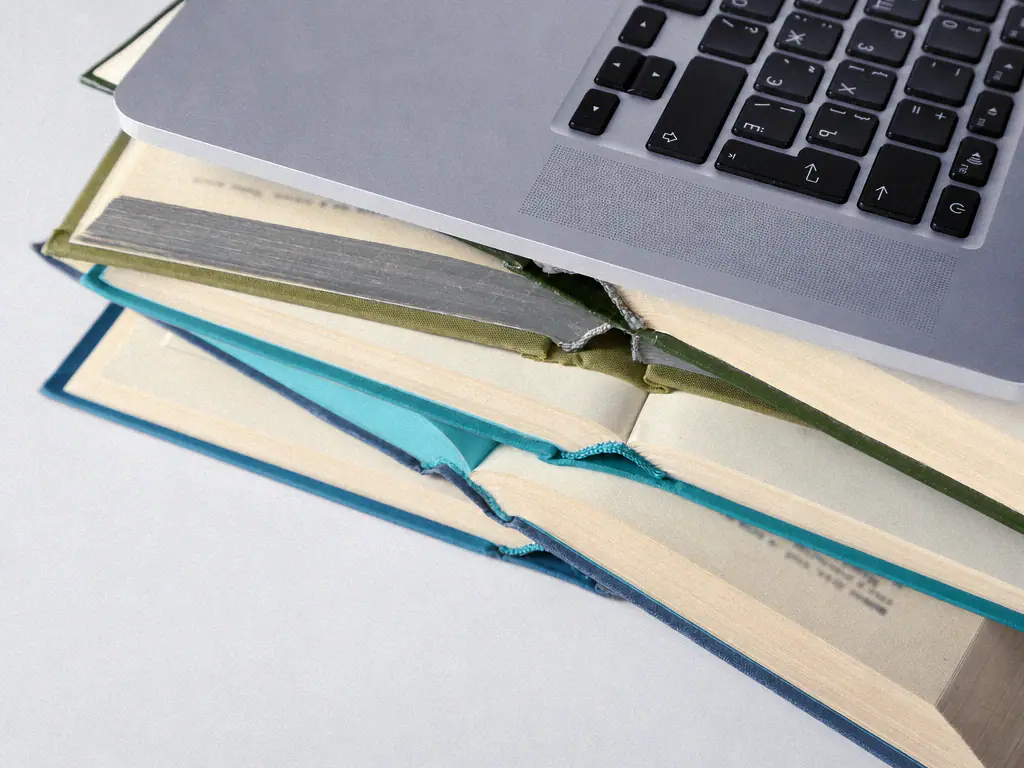 Ordinateur portable posé sur une pile d’ouvrages ouverts
