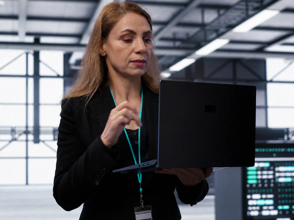 Ingénieure vérifiant un système sur son ordinateur portable dans une salle d’hébergement