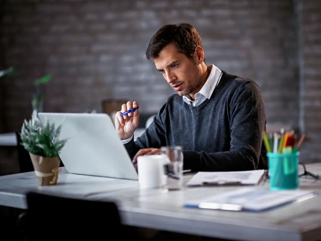 Commercial rédigeant une proposition sur son ordinateur portable, au bureau