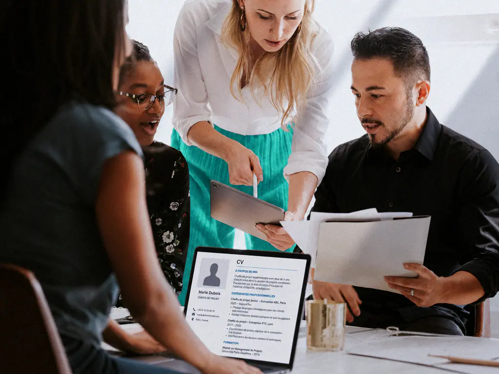 Équipe de recrutement examinant ensemble un CV autour d’une table, ordinateur portable ouvert