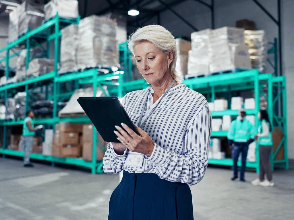 Responsable logistique consultant sa tablette dans un entrepôt