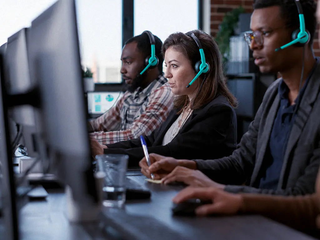 Plateau de support client, trois conseillers au casque devant leurs écrans