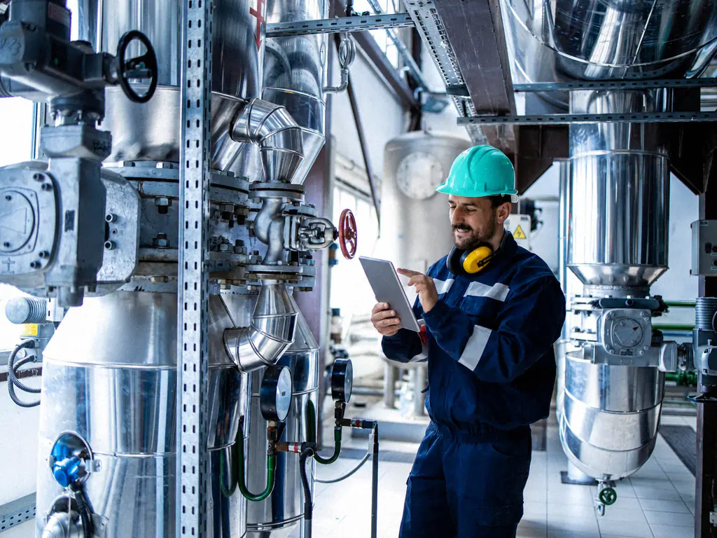 Technicien relevant l’état d’une installation industrielle sur sa tablette
