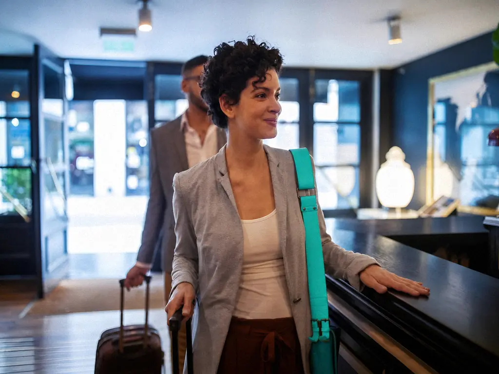 Une voyageuse arrive à la réception d’un hôtel avec sa valise