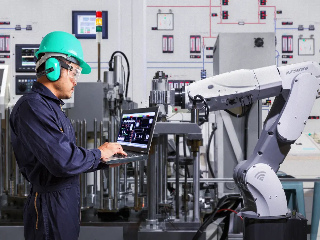 Un technicien pilote une ligne de production robotisée depuis un ordinateur portable