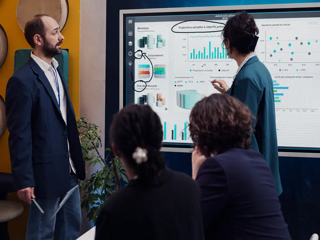 Équipe réunie devant un grand écran d’analyse affichant projections et indicateurs en français