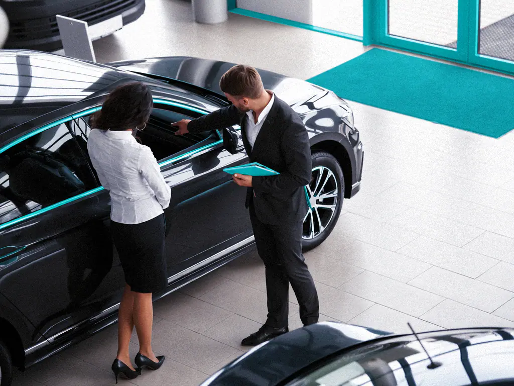 Un conseiller présente un véhicule à une cliente dans une concession automobile