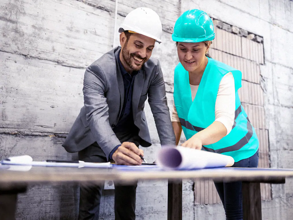 Un ingénieur et une technicienne relisent un plan sur une table de travail