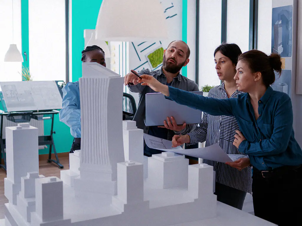 Une équipe d’ingénieurs échange autour d’une maquette blanche dans un bureau d’études