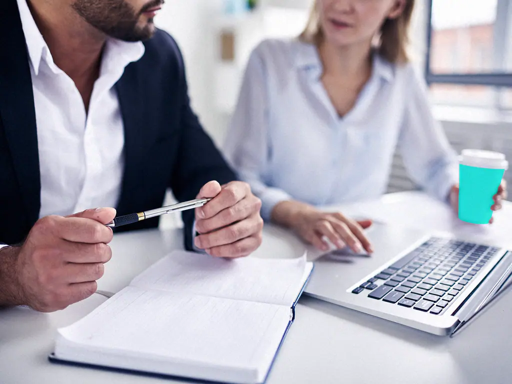 Deux consultants travaillent ensemble sur un ordinateur portable et un carnet de notes