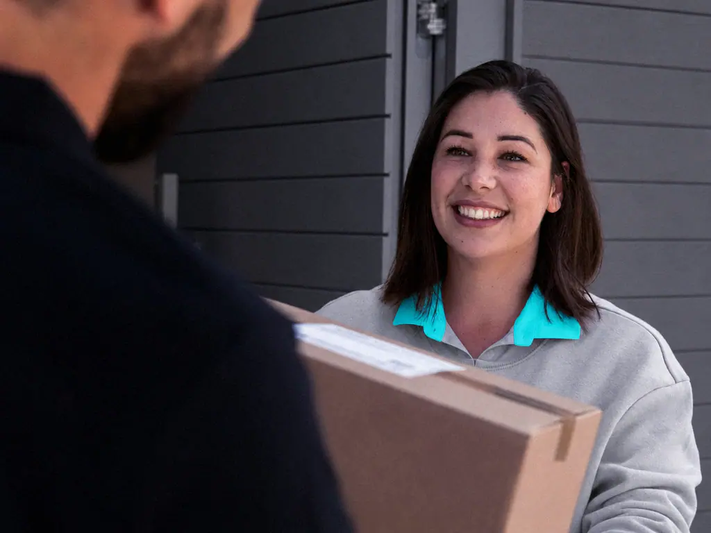 Cliente souriante recevant un colis des mains d’un livreur