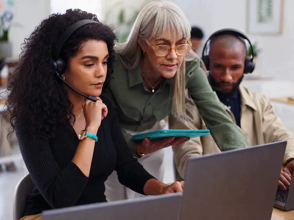 Équipe du service client au casque, réunie autour d’un ordinateur portable