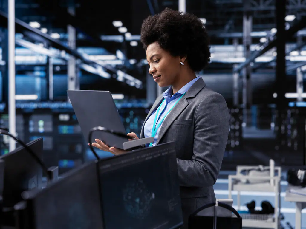 Responsable consultant un ordinateur portable dans une salle informatique industrielle