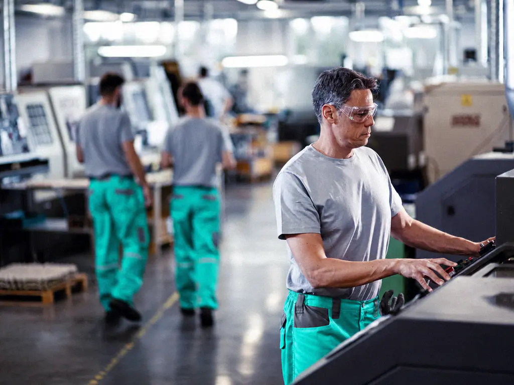 Opérateur en lunettes de protection pilotant une machine-outil dans un atelier de fabrication