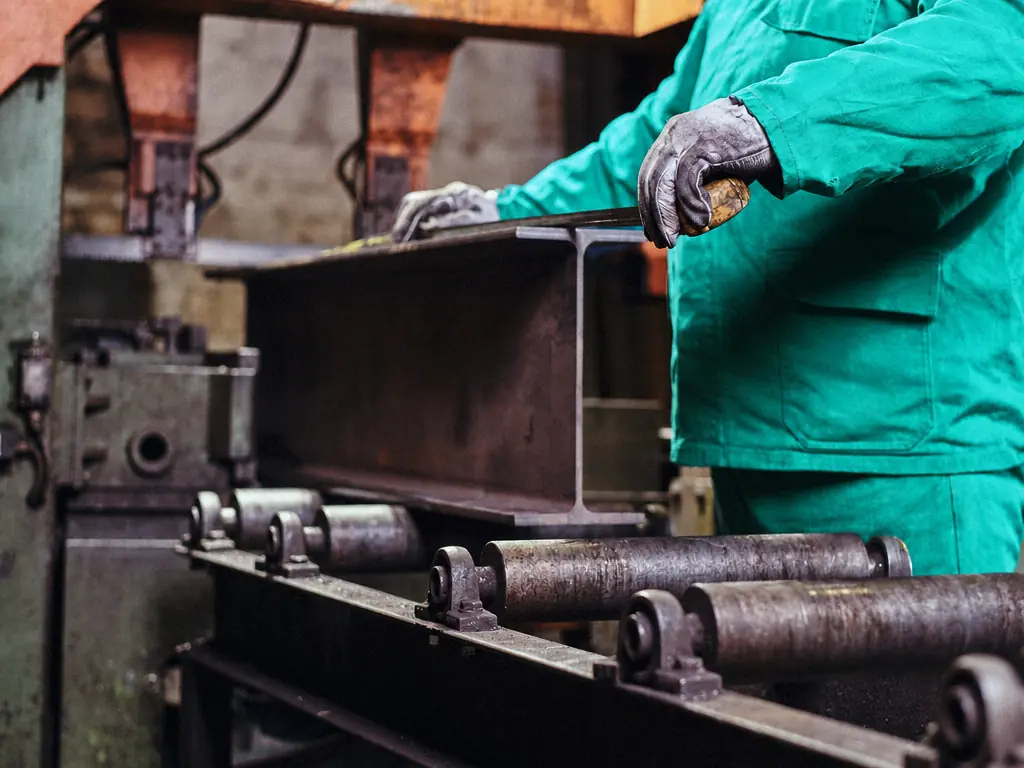 Poutrelle d’acier guidée à la main sur une ligne de rouleaux dans un atelier de métallerie