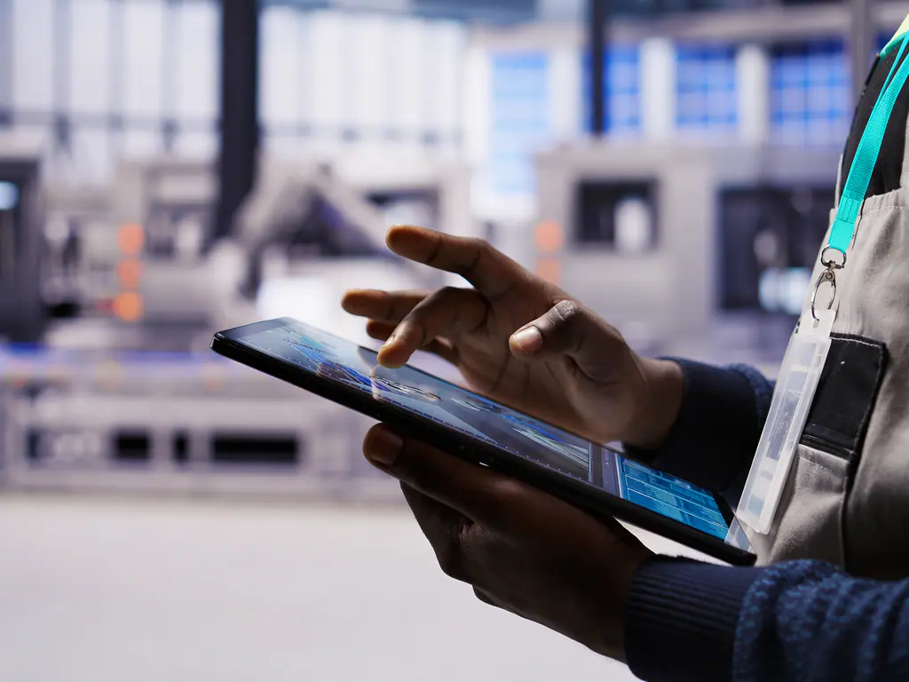 Tablette de pilotage de la production tenue devant une ligne automatisée