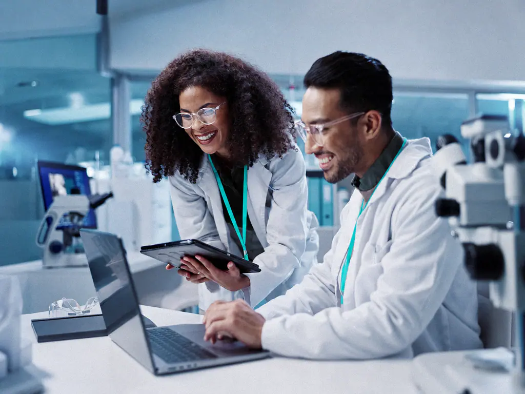 Deux biologistes en blouse consultent des résultats sur un ordinateur portable