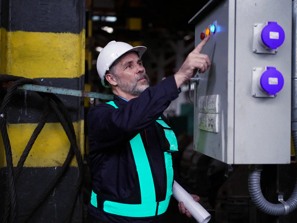 Technicien de maintenance en casque intervenant sur une armoire électrique en usine