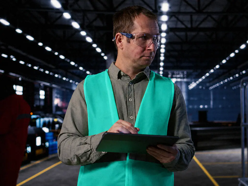 Un responsable d’atelier consulte une tablette dans une halle de production