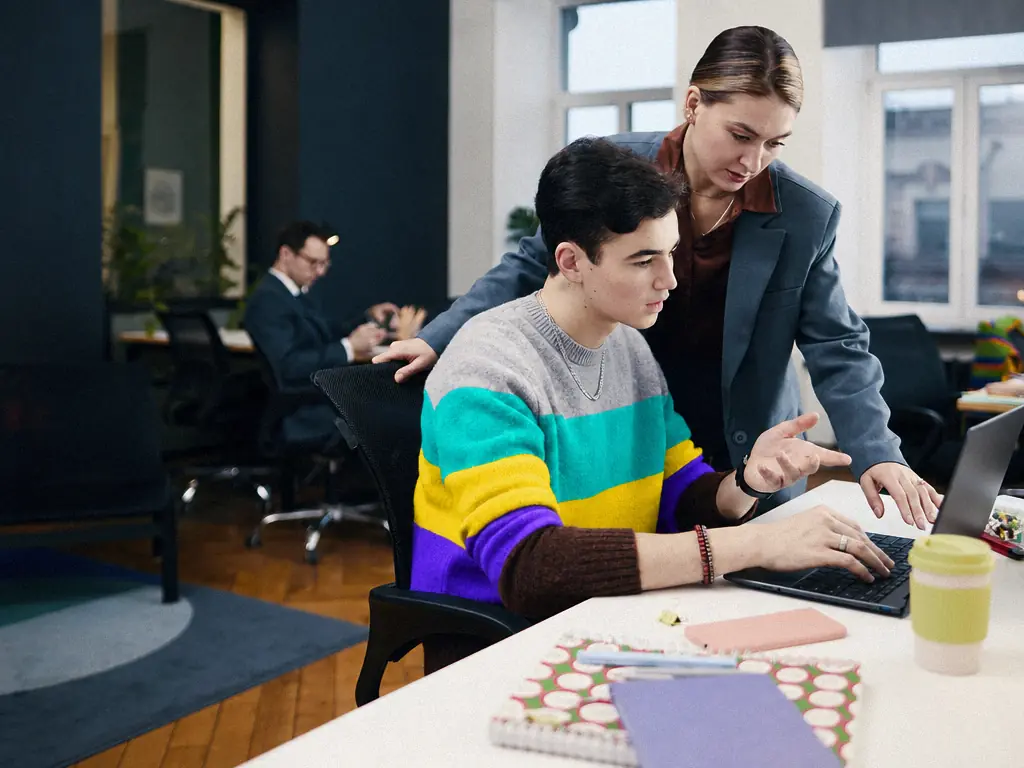 Collègue accompagnant un nouveau collaborateur devant son ordinateur, au poste de travail