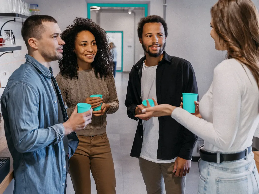 Collègues échangeant autour d’un café dans un espace de travail lumineux