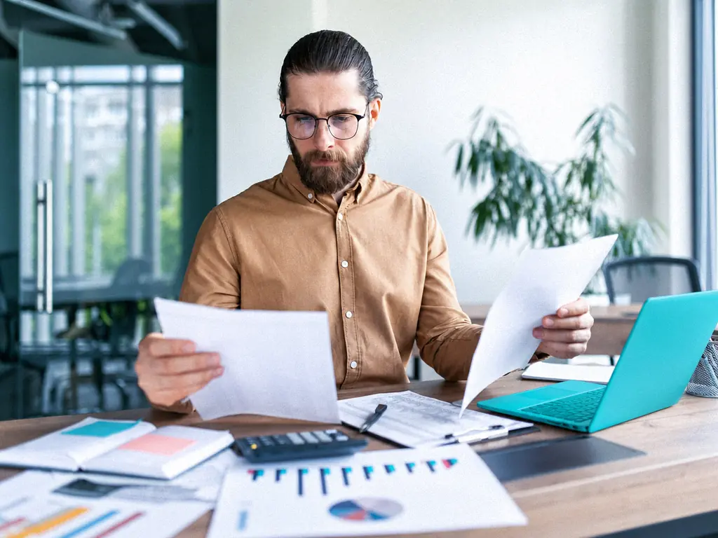Responsable financier analysant des relevés chiffrés et des graphiques imprimés à son bureau