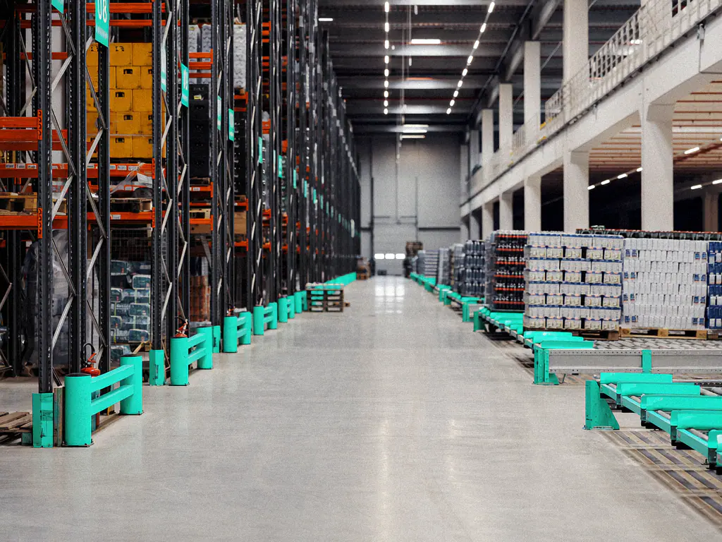 Longue allée d’entrepôt bordée de rayonnages et de palettes de produits