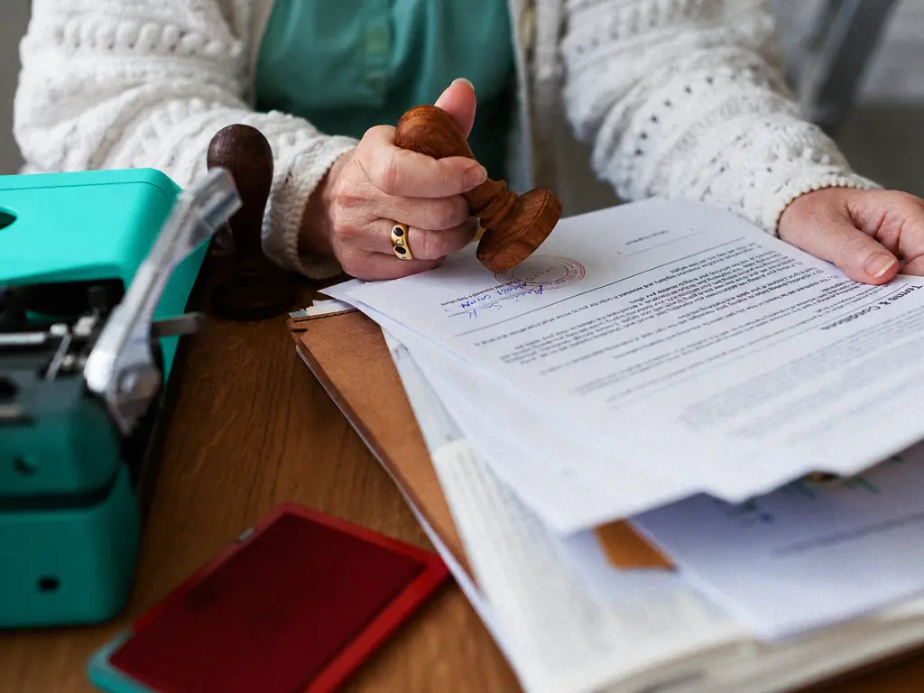 Main apposant un tampon sur une liasse de documents administratifs