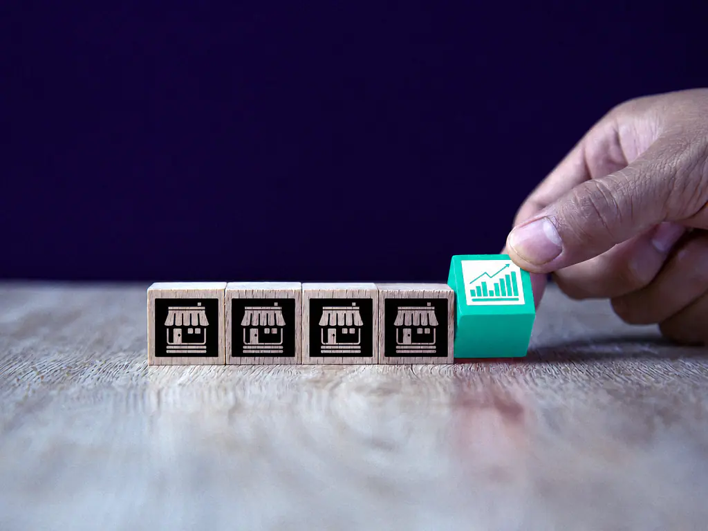 Des cubes de bois portant des pictogrammes de magasins, alignés sur une table