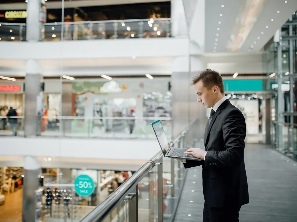 Un responsable consulte un ordinateur portable sur la coursive d’un centre commercial