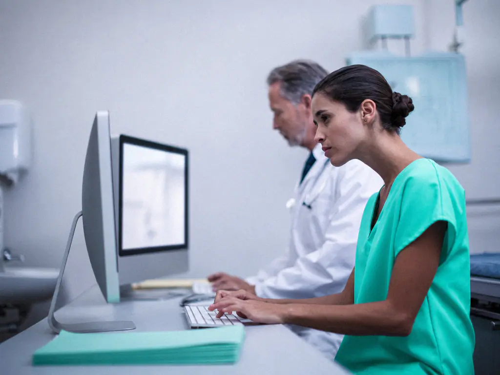 Un médecin et une infirmière travaillent à leur bureau devant un écran