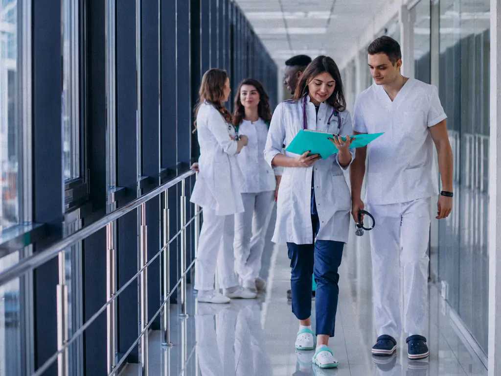 Une équipe de soignants en blouse marche dans un couloir de clinique