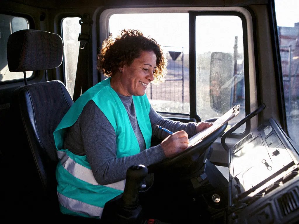 Une conductrice remplit un bon de livraison dans la cabine de son camion