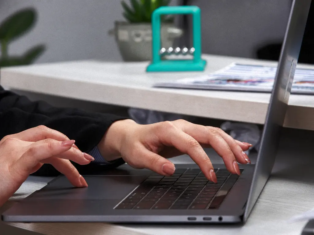 Mains sur le clavier d’un ordinateur portable, bureau clair
