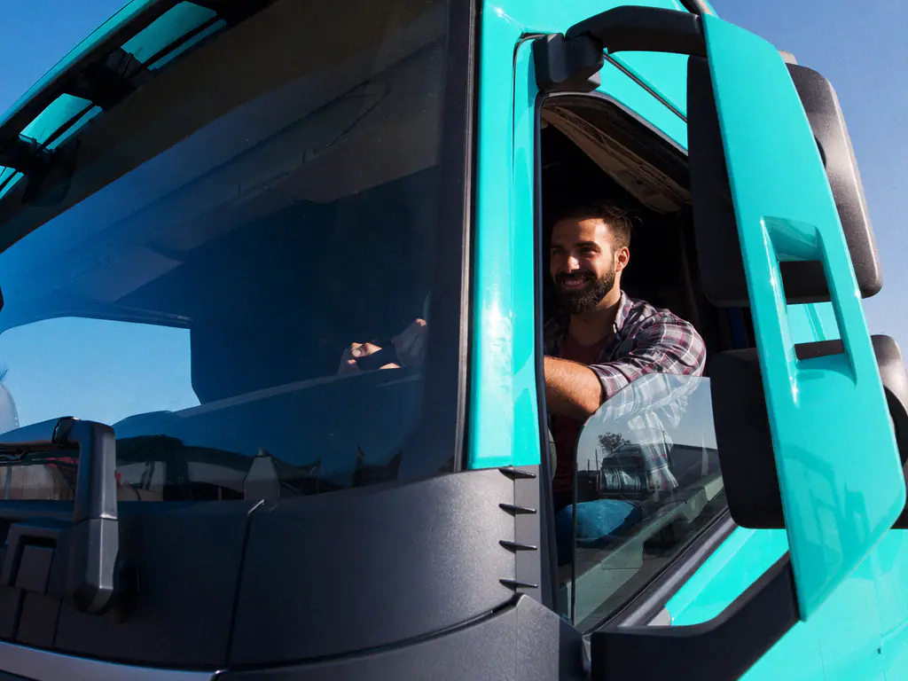 Chauffeur souriant au volant de son camion turquoise